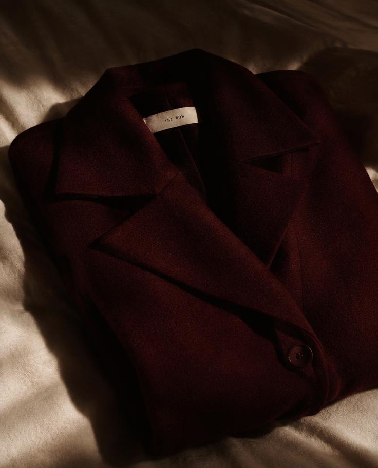Oversized burgundy wool coat folded on linen